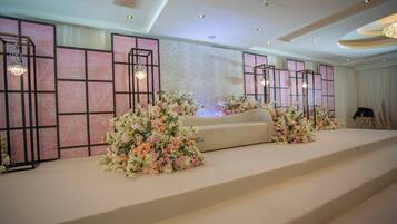 Un escenario con arreglos florales y un sofá, frente a una pared con diseño geométrico e iluminación empotrada.