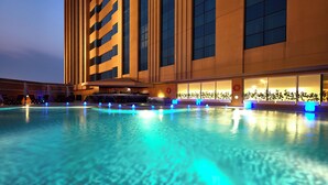 A hotel pool area with a large pool, lounge chairs, and a bar area. - Millennium Hotel and Convention Centre Kuwait (Salmiya)