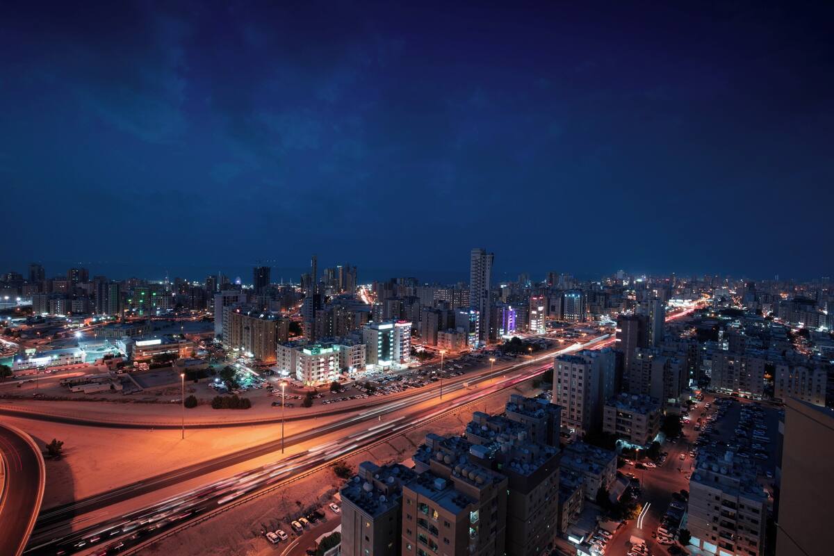 Une vue nocturne d’une ville, avec des bâtiments illuminés et une autoroute très fréquentée.
