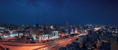A nighttime cityscape with illuminated buildings and a busy highway.