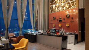 A modern bar area with a city view, featuring a bar counter, seating, and decorative wall elements. - Millennium Hotel and Convention Centre Kuwait (Salmiya)