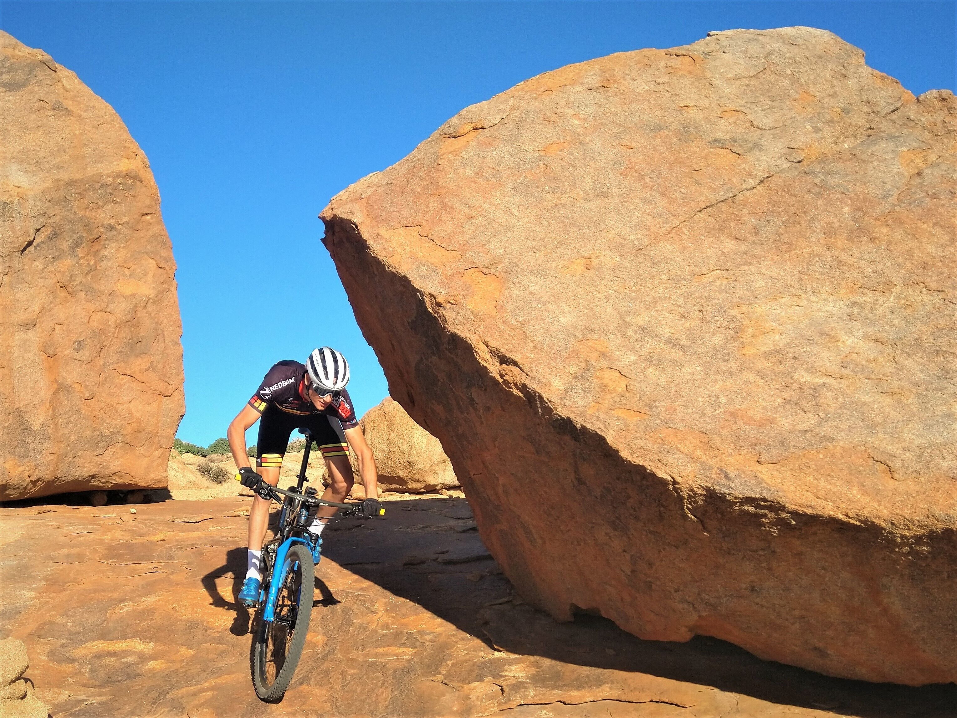 Un ciclista pedaleando por un terreno rocoso con grandes rocas.