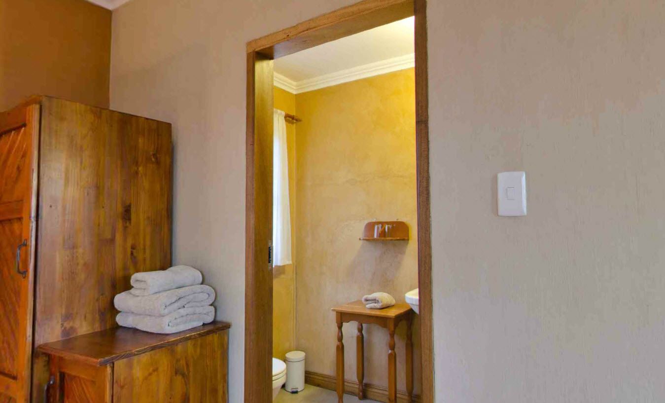 Un baño con un armario de madera, una mesita con una toalla y un inodoro.