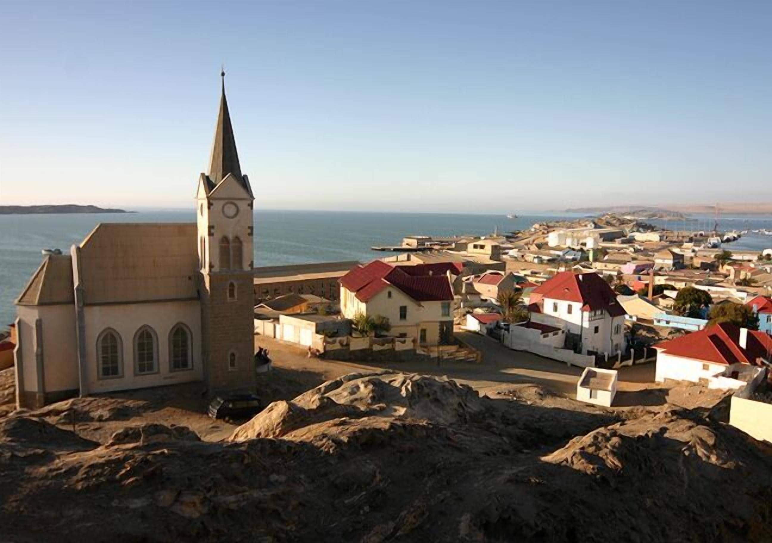 Un pueblo costero con una iglesia destacada, terreno rocoso y vista al mar.