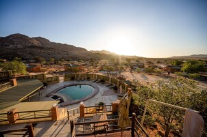 Un área de piscina con un jacuzzi circular, rodeado por un deck de madera y una valla.