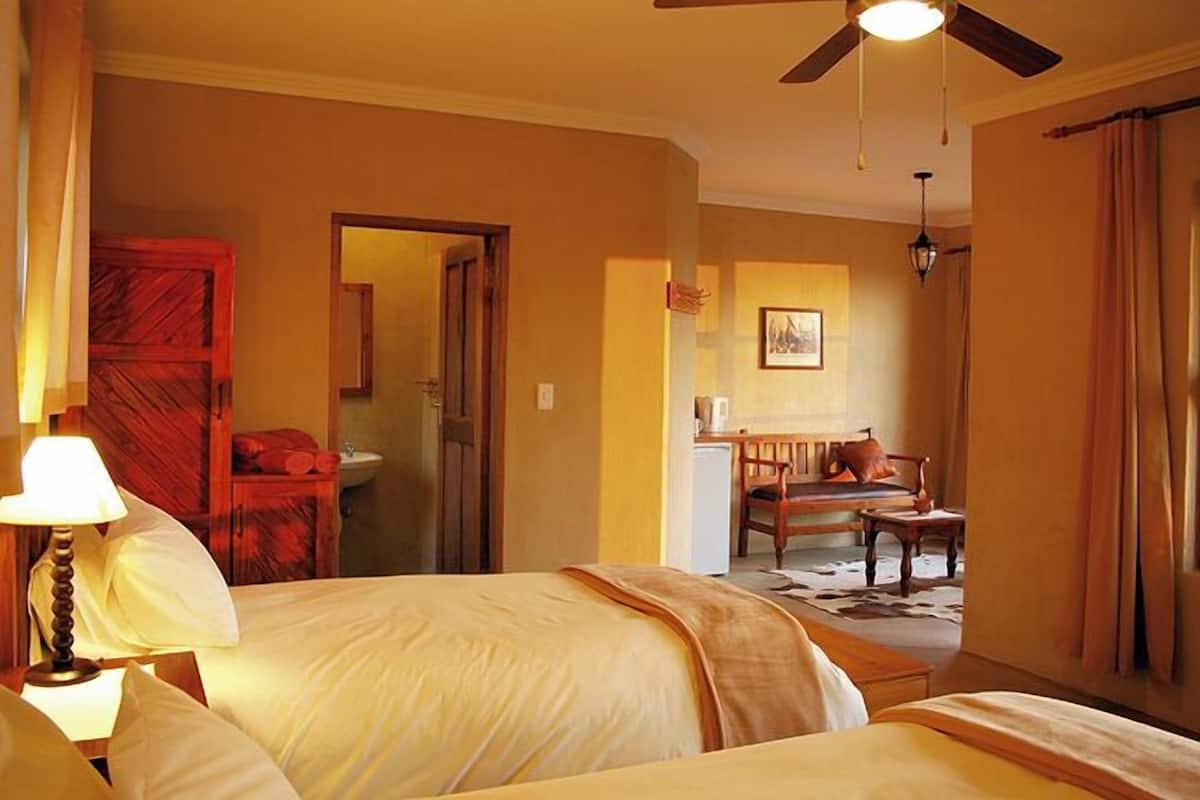 A hotel room with two beds, a ceiling fan, a desk, and a chair.