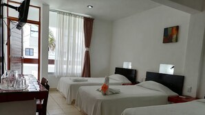 A hotel room with two beds, a dining table, and a TV. - Hotel Plaza Carrillo's (Cancun)