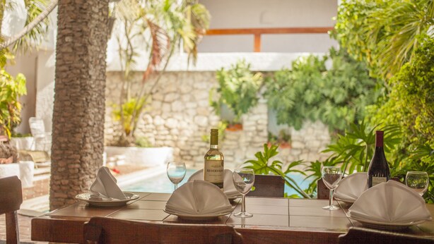 A table set for dining with a bottle of wine, glasses, and a menu. - Hotel Plaza Carrillo's (Cancun)