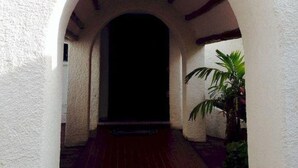 An arched entrance with a red brick pathway leading to a dark doorway. - Hotel Plaza Carrillo's (Cancun)