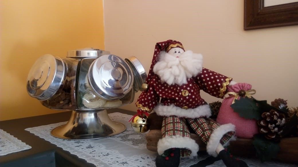 A table with a decorative metal container and a Santa Claus figurine.