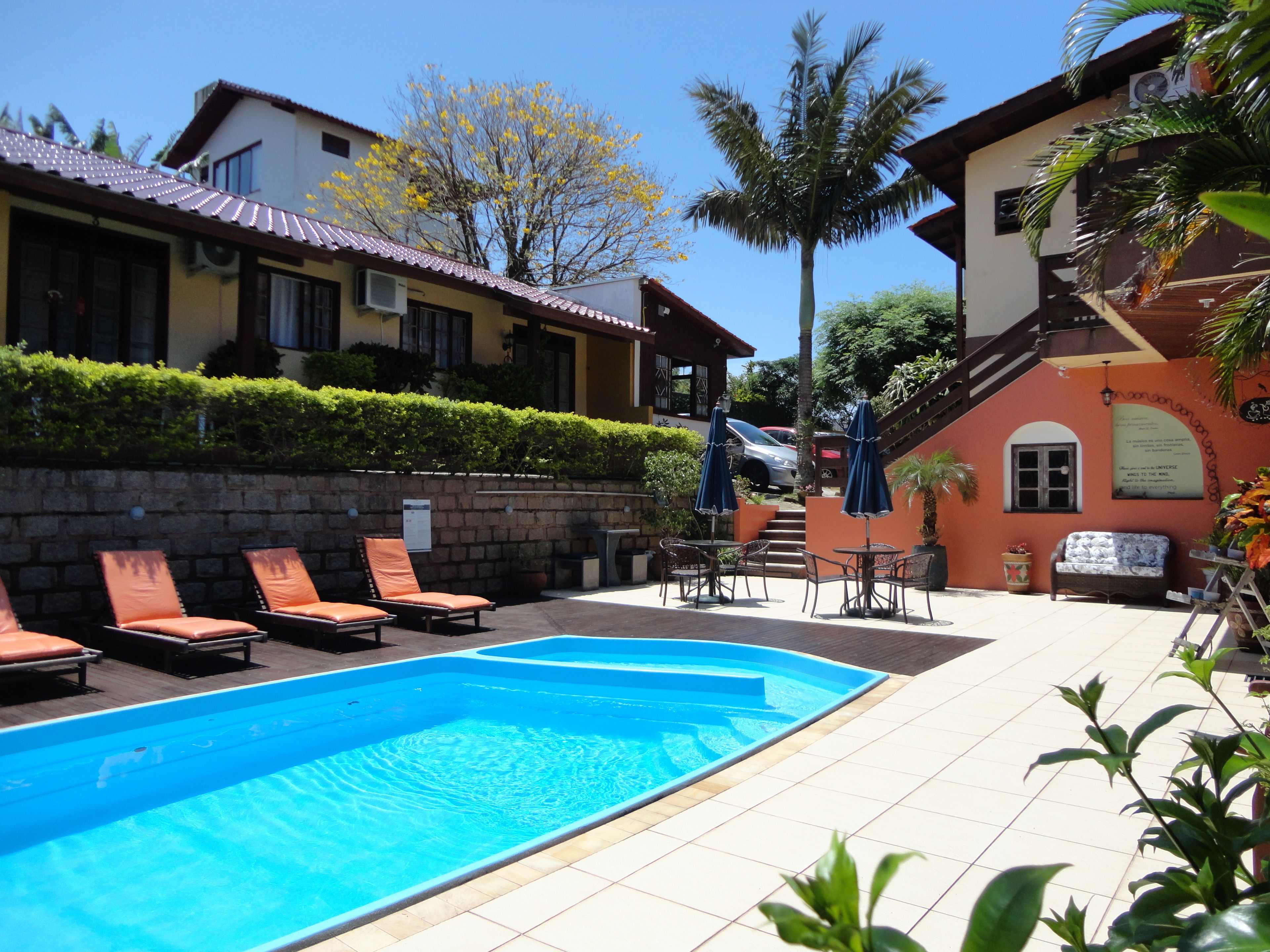 Uma piscina com espreguiçadeiras, uma escadaria e um edifício com uma placa.