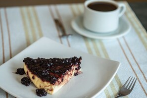 A slice of pie on a white plate with a fork beside it, and a cup of coffee on a striped tablecloth. - Pousada do Atobá (Florianópolis)