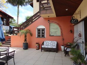 A patio area with a wicker sofa, a potted plant, and a table with chairs. - Pousada do Atobá (Florianópolis)