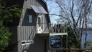 Una cabaña de madera con balcón y un panel solar.