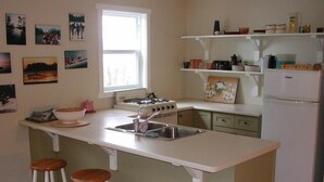 Una cocina con una isla central, taburetes de bar, un refrigerador y una ventana.