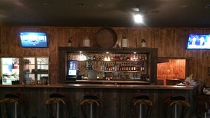 A bar area with wooden paneling, a bar counter, and stools. - Mountain Ridge Cabins and Lodging (Hatch)