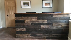 A reception desk with a wooden finish and a light fixture above it. - Mountain Ridge Cabins and Lodging (Hatch)