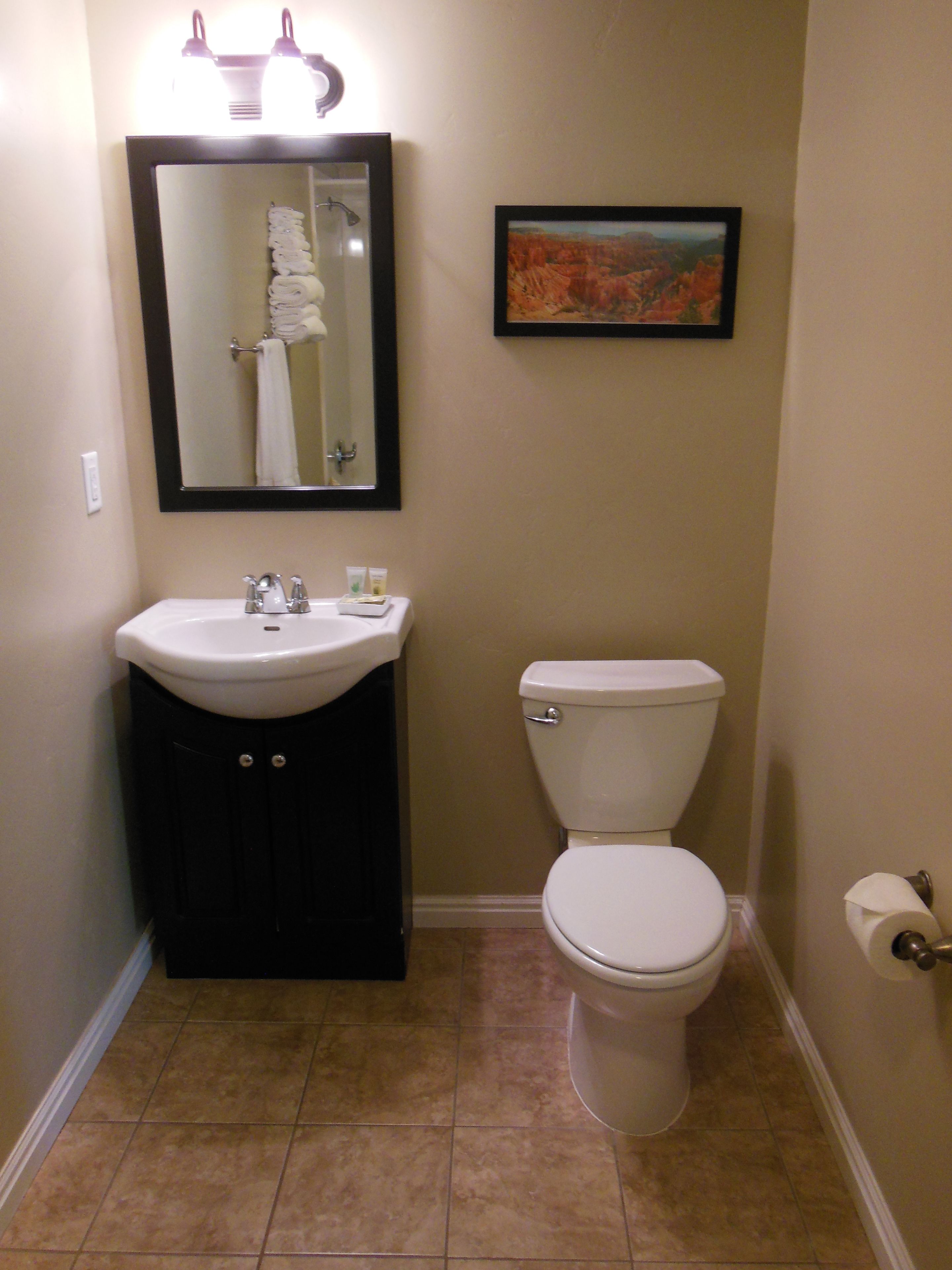 A bathroom with a sink, toilet, and a framed picture on the wall.