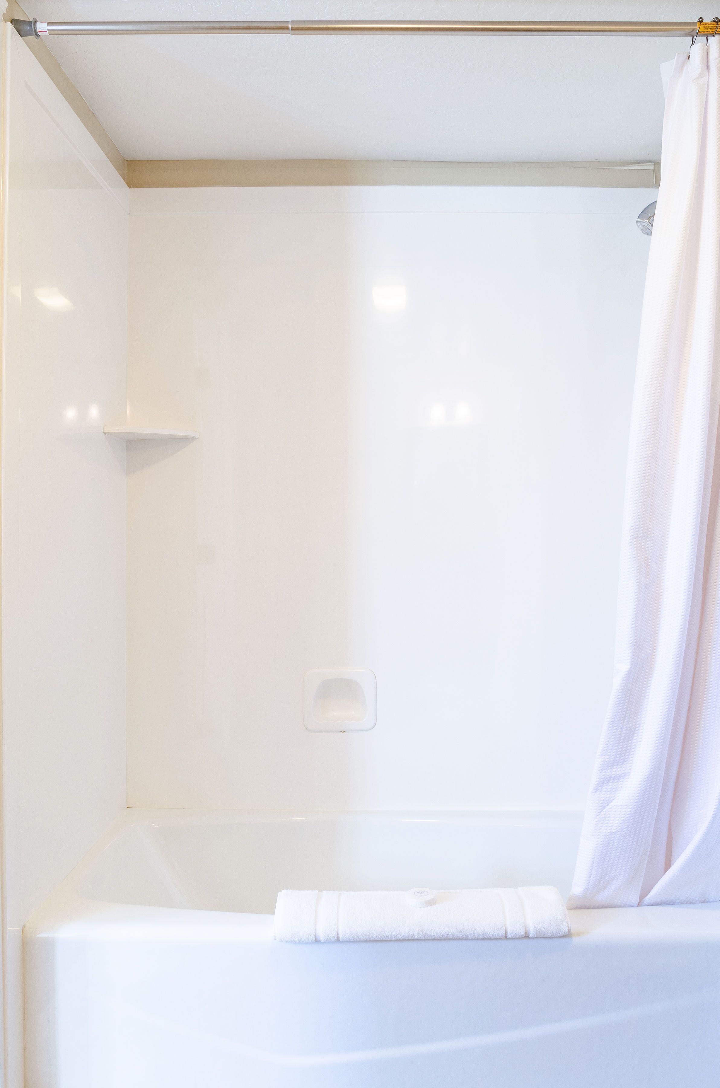 A modern bathroom with a bathtub, a shower curtain, and a towel placed on the edge of the tub.