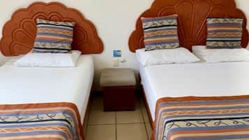 Habitación de hotel con dos camas, cada una con colcha estampada y almohadas a juego. Entre las camas, una mesita de noche con una lámpara.