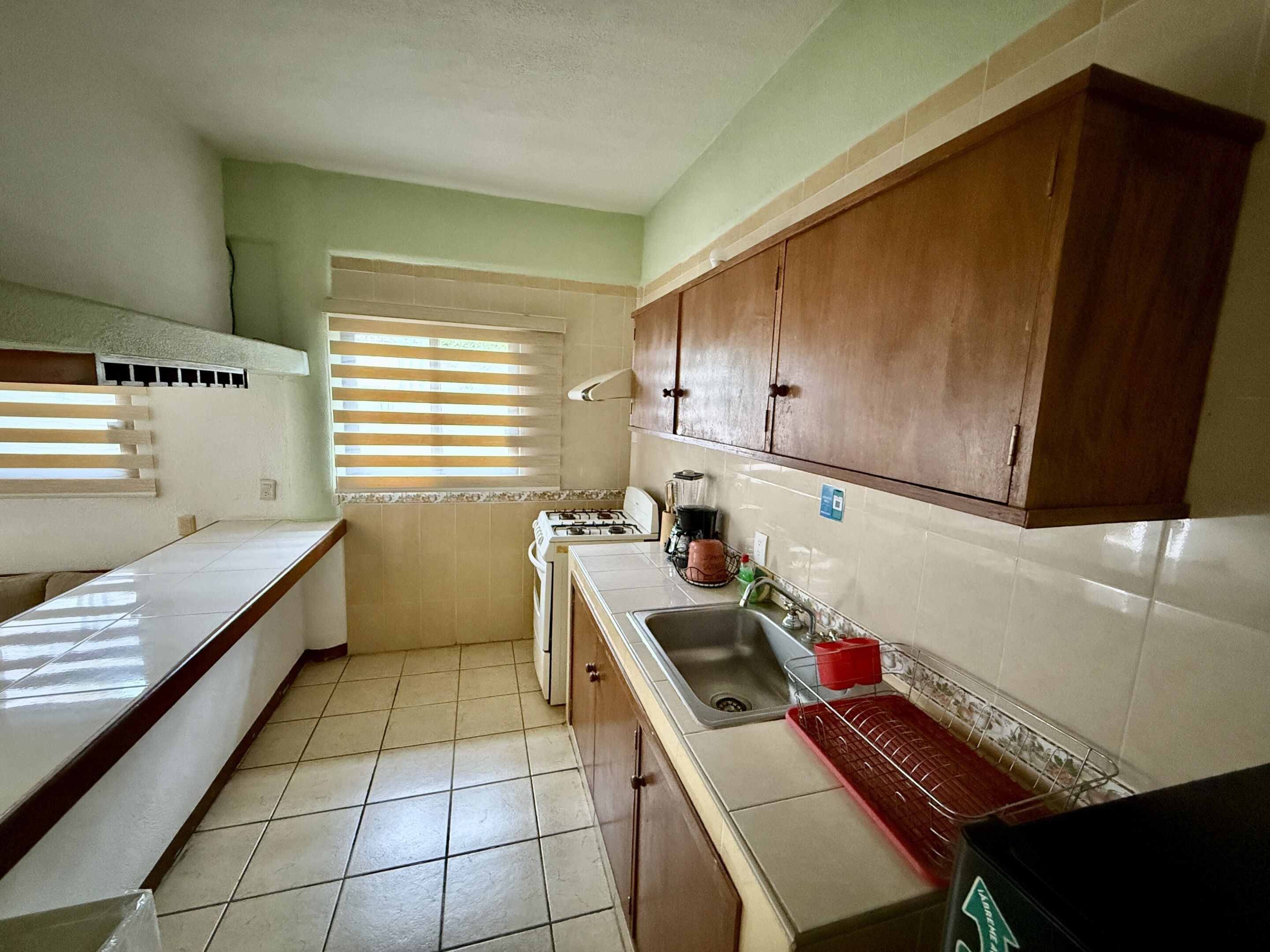 Una cocina con estufa, pileta y armarios de madera.
