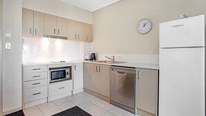 Una cocina moderna con armarios blancos, electrodomésticos de acero inoxidable y un reloj en la pared.