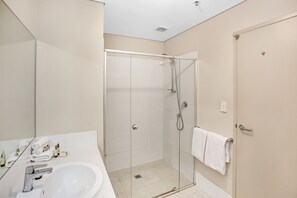 Un baño moderno con cabina de ducha de vidrio, un lavabo blanco y un espejo.