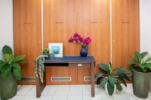Una recepción con un jarrón de flores, un cuadro enmarcado y plantas en macetas.