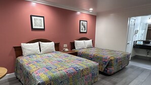 A hotel room with two beds, each with a colorful quilt, a small bedside table, and a telephone. - Willow Tree Lodge (Fullerton)