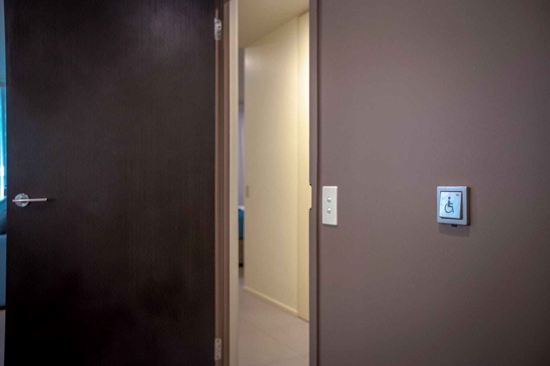 A hallway with a door leading to a room with a wheelchair accessibility sign.