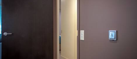 A hallway with a door leading to a room with a wheelchair accessibility sign.