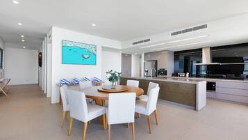 Una cocina moderna con una isla central, una zona de comedor con una mesa redonda y sillas, y un cuadro grande en la pared.
