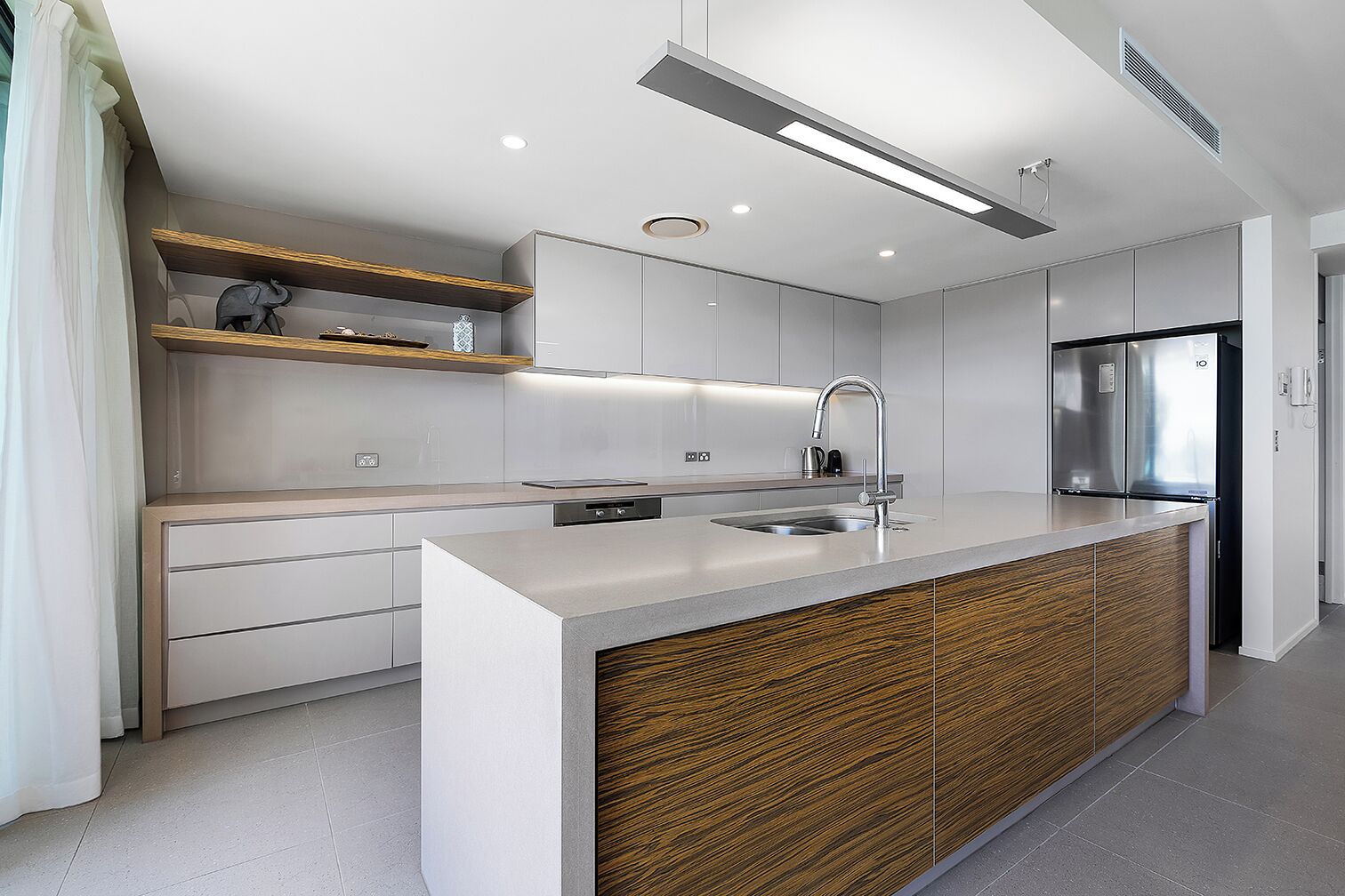 A modern kitchen with a central island, stainless steel appliances, and a wooden accent wall.