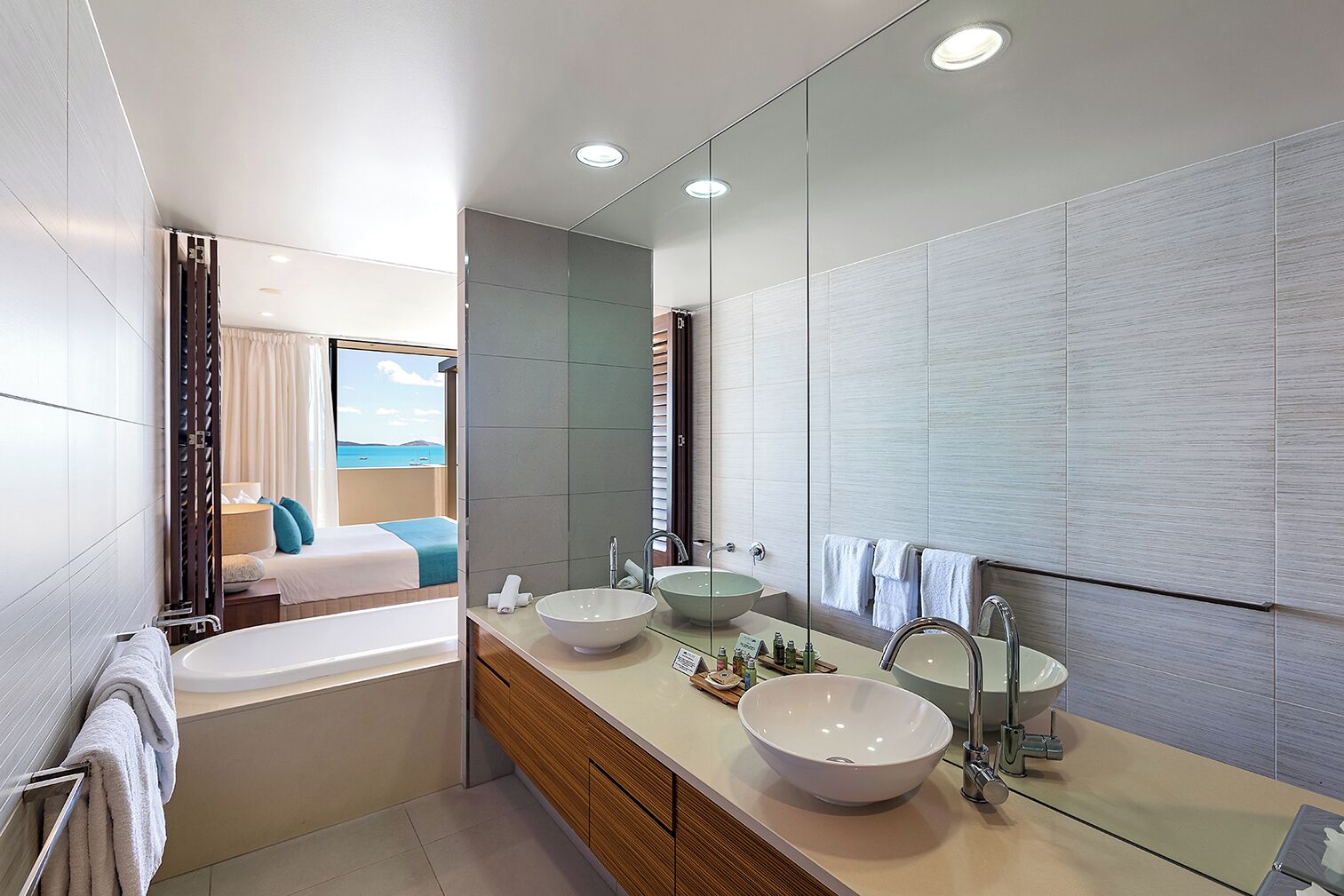 A modern bathroom with a bathtub, two sinks, and a large mirror.