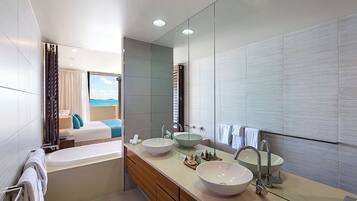 A modern bathroom with a bathtub, two sinks, and a large mirror.