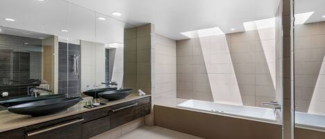 A modern bathroom with two large black sinks, a large mirror, and a walk-in shower.