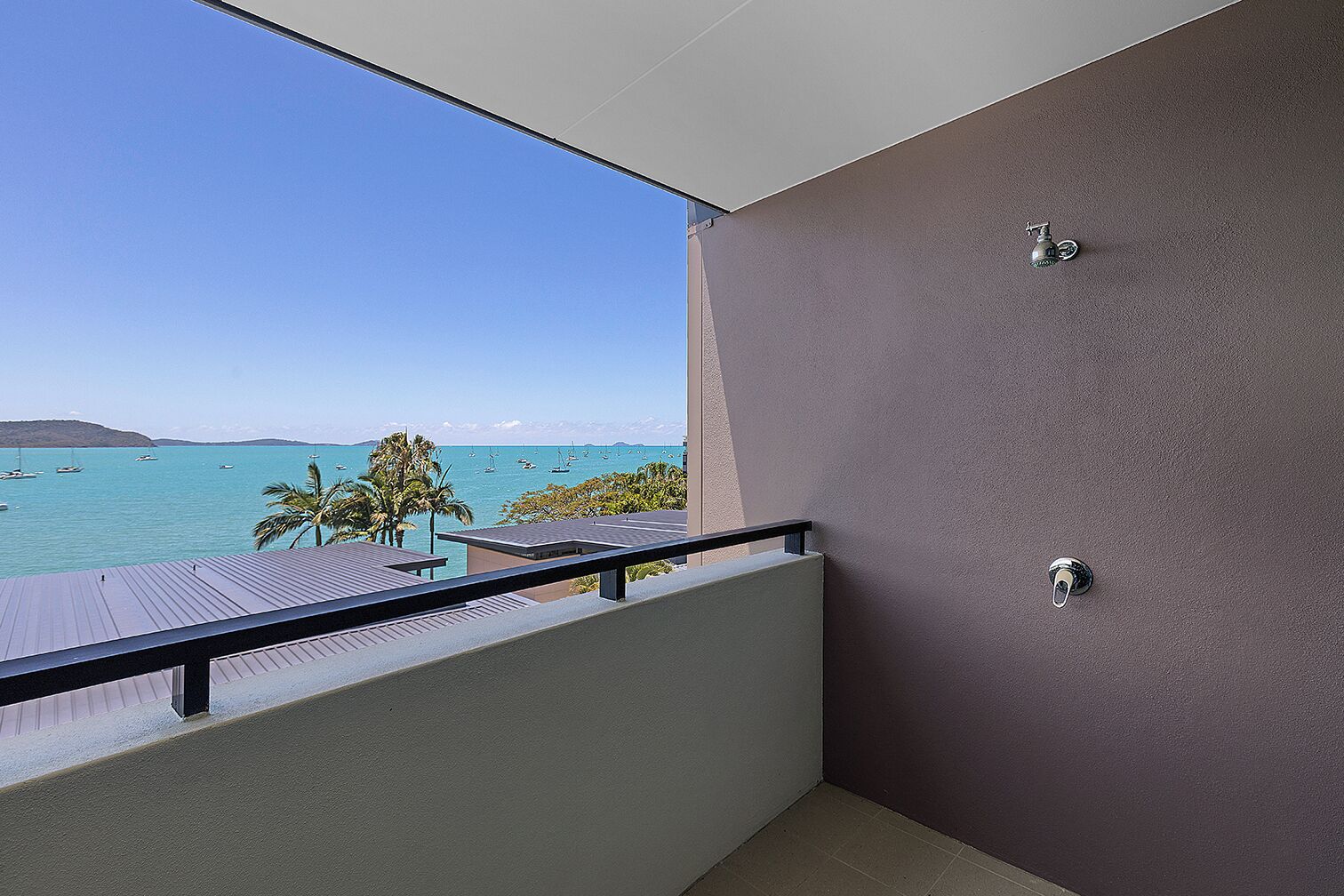A balcony with a view of the sea, a door, and a window.