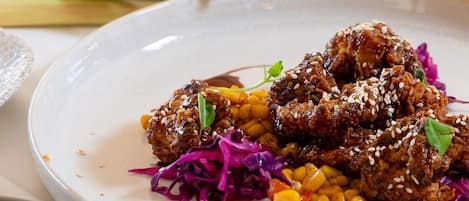 A variety of dishes on a table, including meatballs with sesame seeds, corn, and purple cabbage.