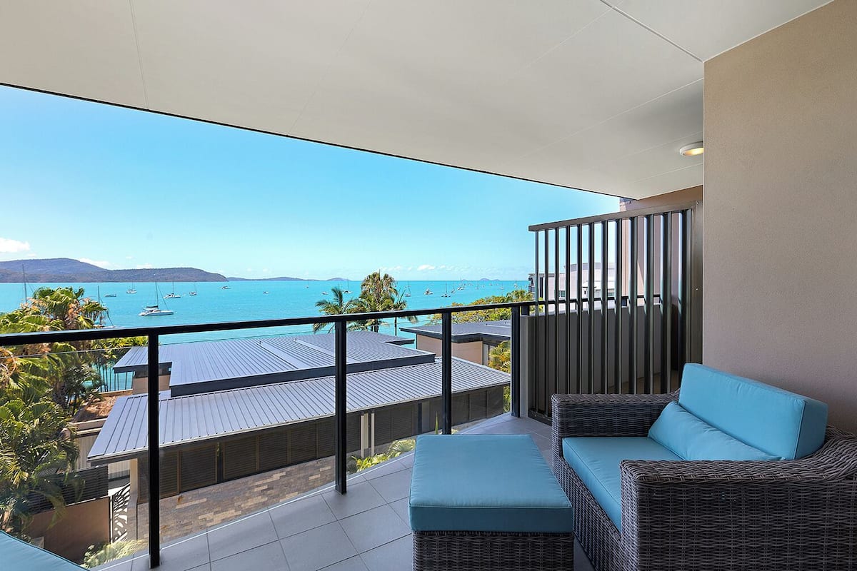 Un balcon doté de meubles en osier et offrant une vue sur la mer.