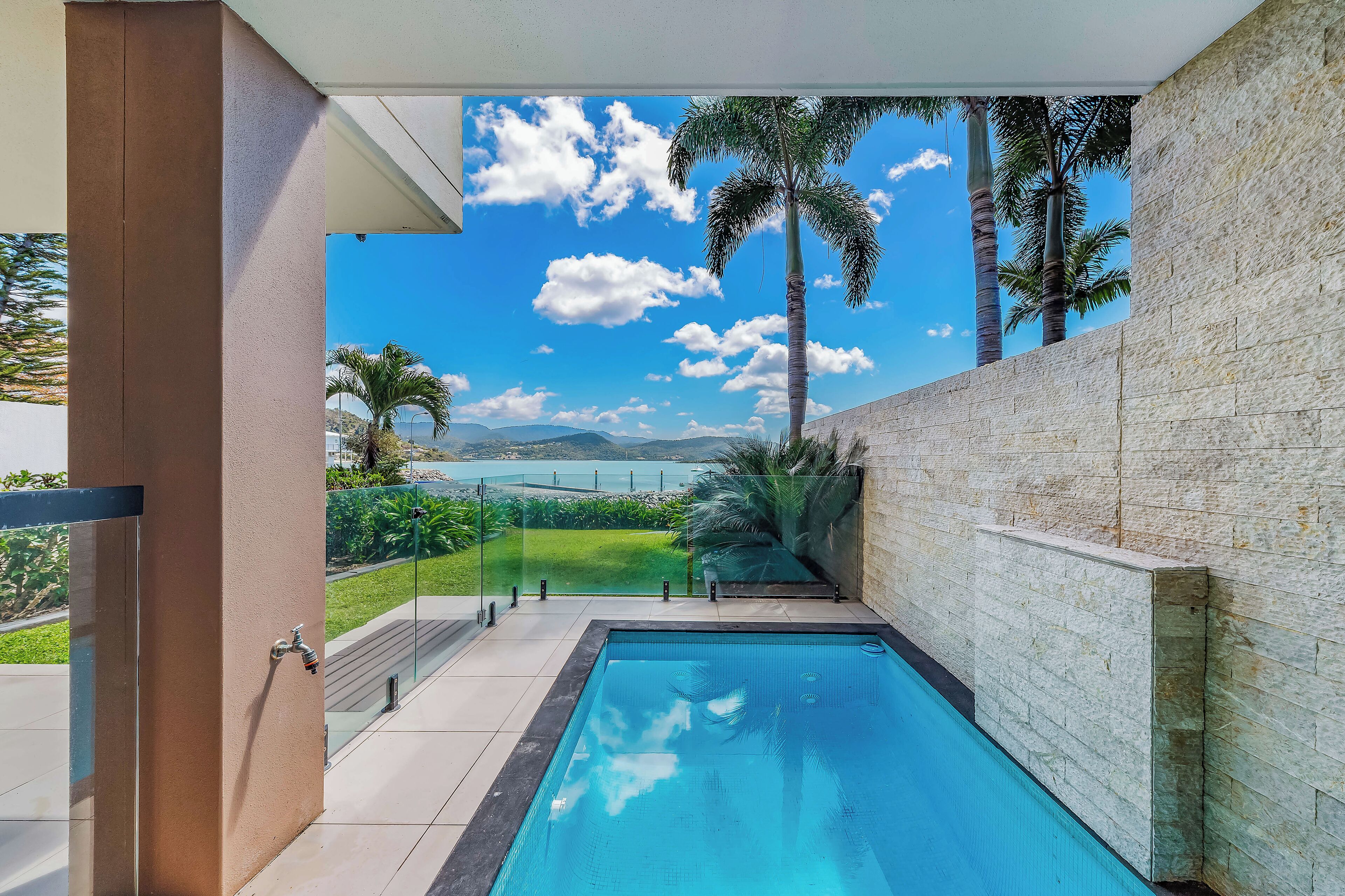 Een modern zwembad met uitzicht op een helder meer en bergen.