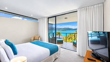 Habitación de hotel con cama, televisión, balcón y vistas al mar, además de una silla.