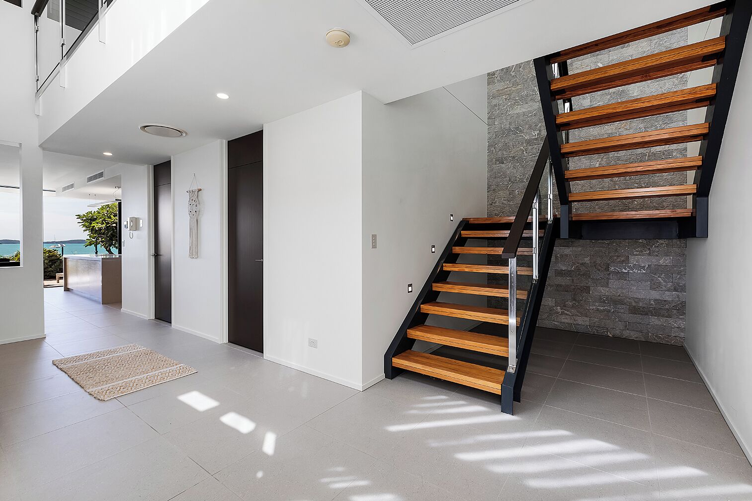 A modern interior with a staircase, a view to the outside, and a minimalist design.