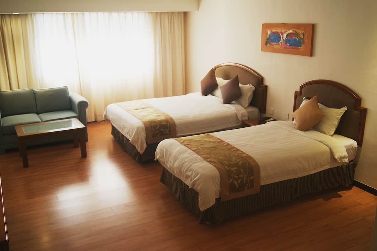 A hotel room with two beds, a sofa, and a painting on the wall.