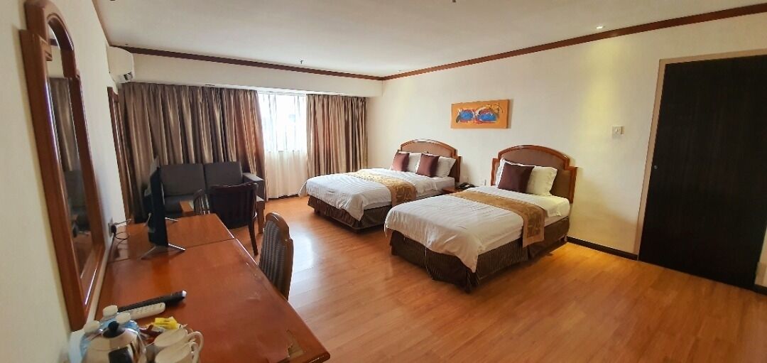 A hotel room with two beds, a desk, a chair, a mirror, and a painting on the wall.