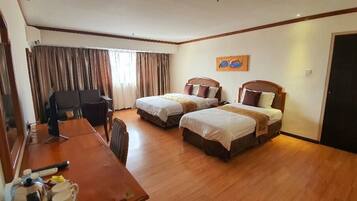 A hotel room with two beds, a desk, a chair, a mirror, and a painting on the wall.