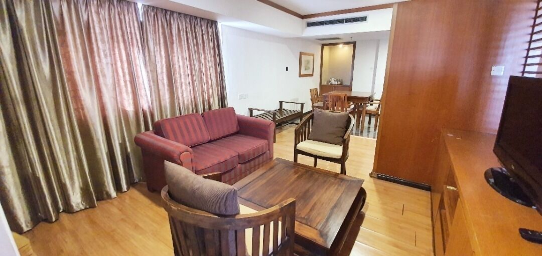 A living room with a sofa, armchair, and coffee table. There is a dining table with chairs in the background.