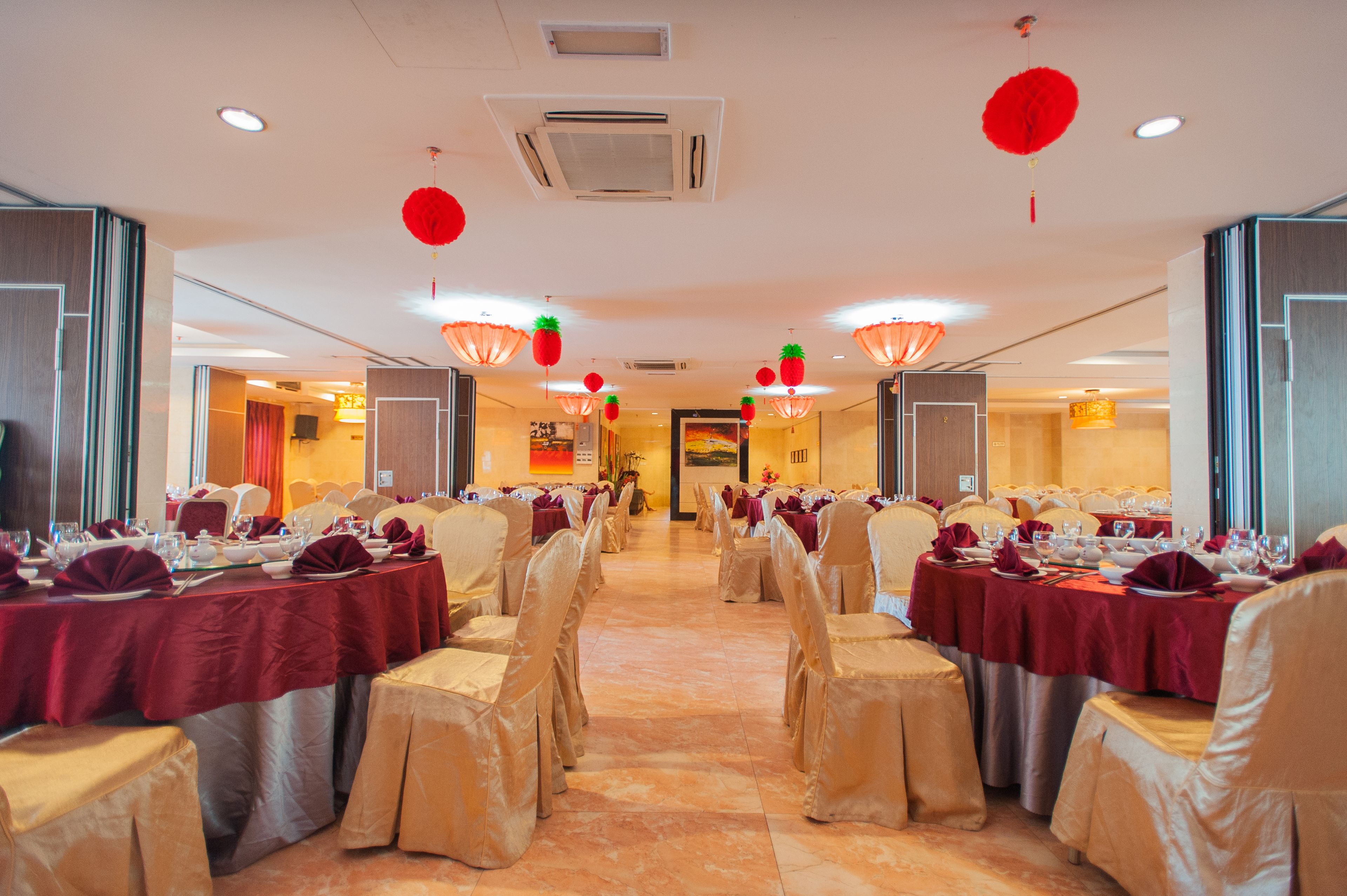 A banquet hall with tables set for a formal event, featuring a central aisle and rows of tables with chairs.