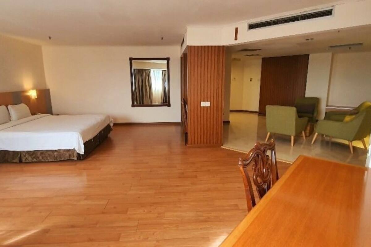 A hotel room with a bed, bedside table, and a wooden desk.