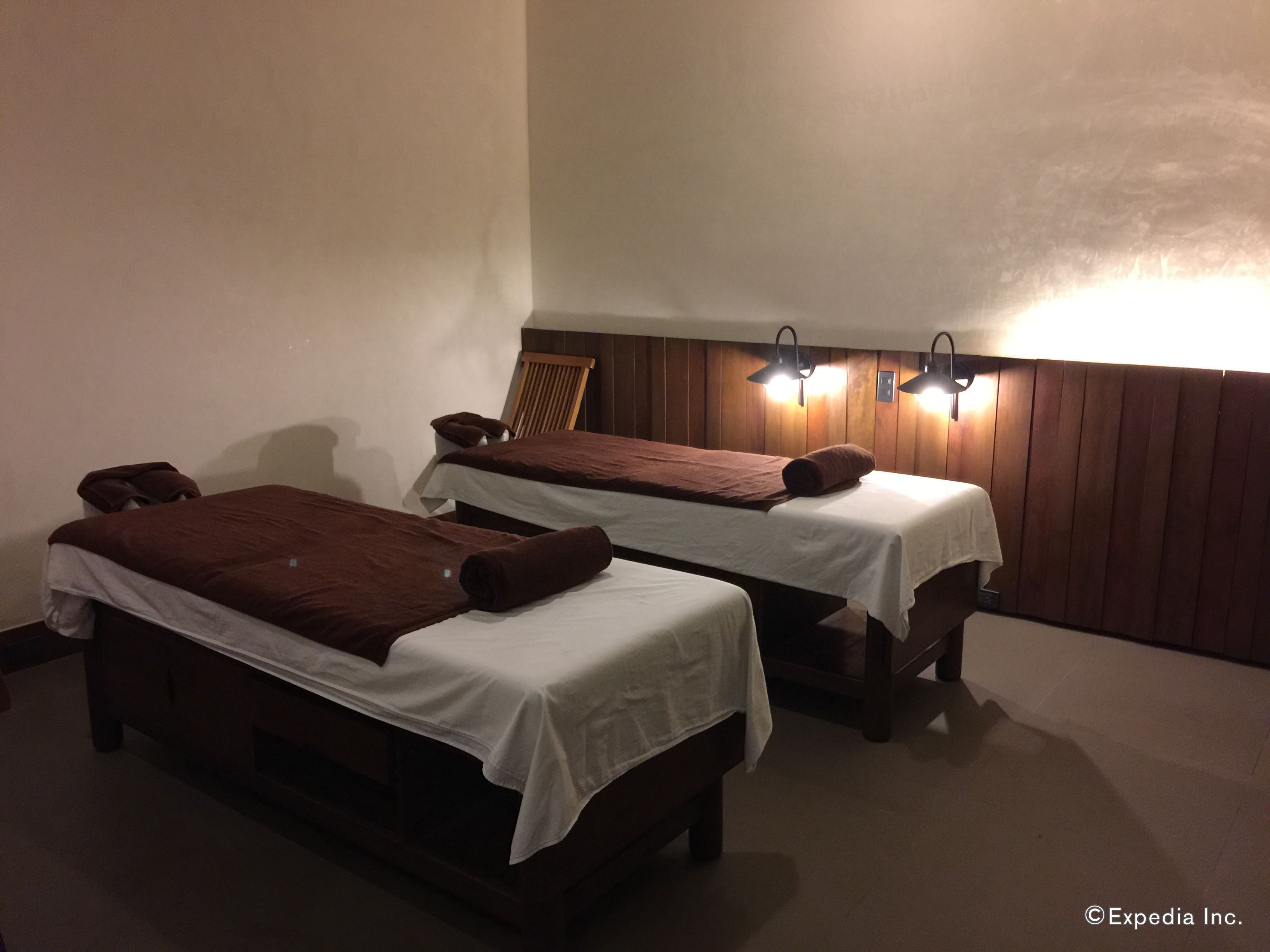 Two single beds with brown towels, wooden headboards, and wall-mounted lights.