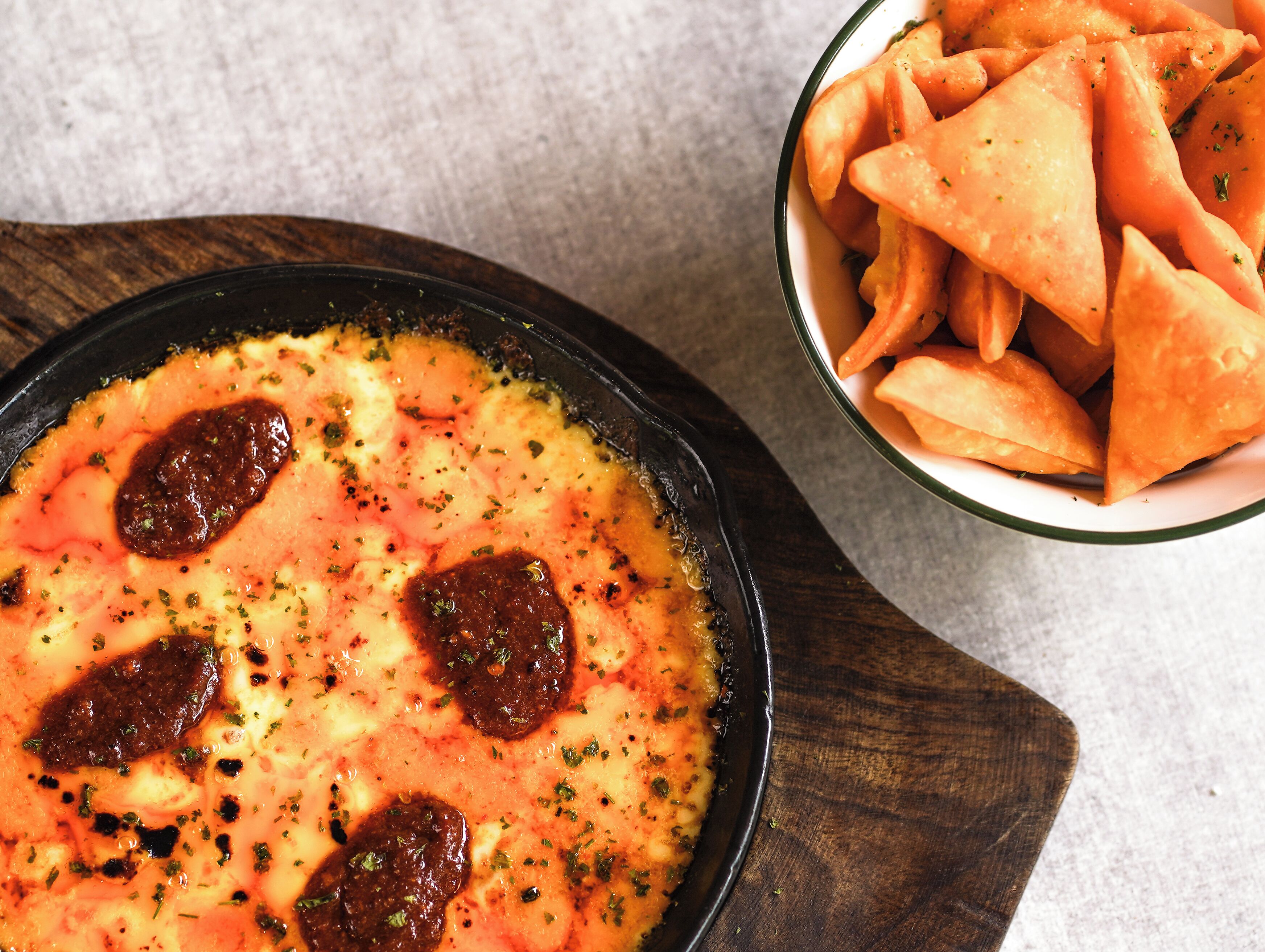 A bowl of soup with herbs and a side of samosas.